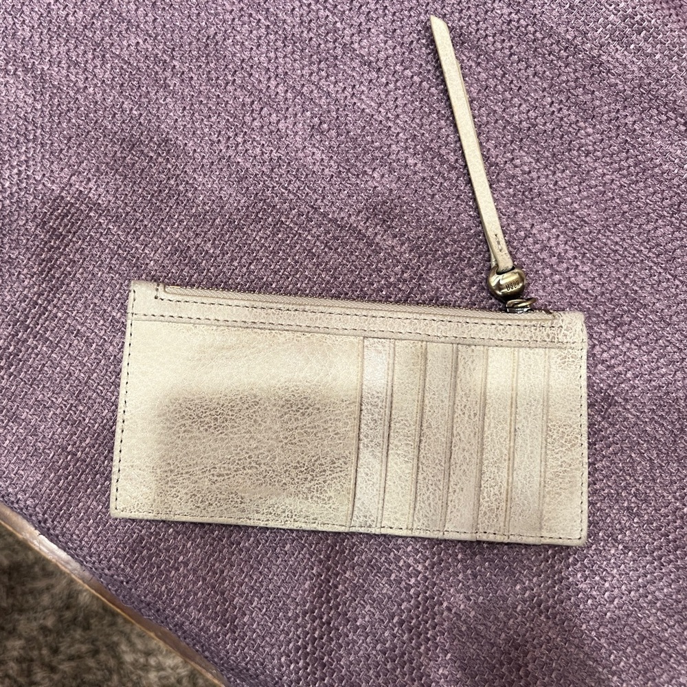 HOBO flat cream/gold leather wallet with zipper top for bills and change.
